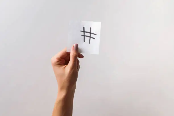 Photo of Woman's hand holding small paper with drawn hashtag symbol on it