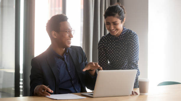 istock Smiling multiethnic diverse colleagues talk cooperating at laptop 1159741267