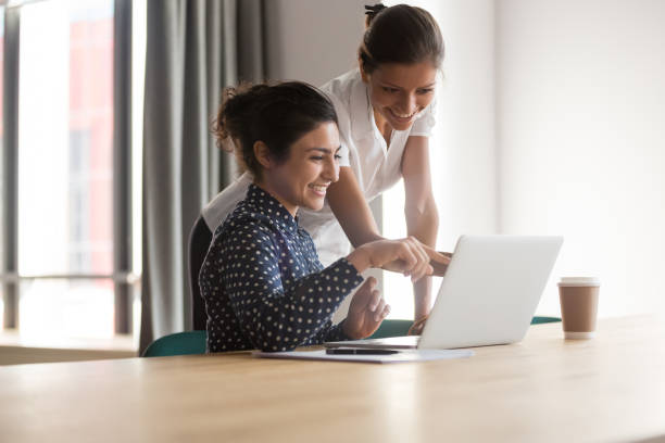 istock Smiling diverse colleagues talk discussing ideas working on laptop 1159741268