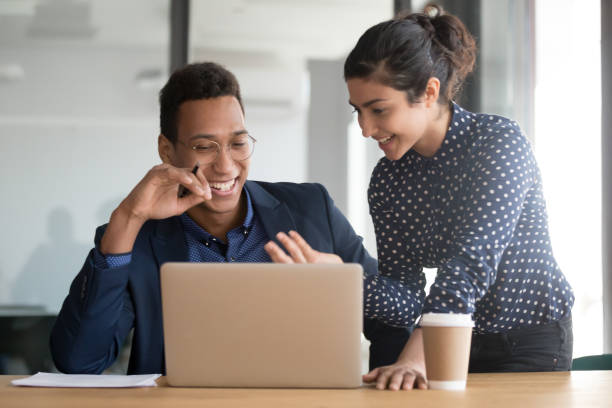 istock Smiling multiethnic colleagues laugh discussing business ideas at laptop 1159741289