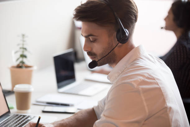 istock Serious male worker in headset make notes consulting client online 1159741298