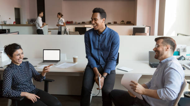 Smiling multiethnic colleagues laugh talking at informal team meeting