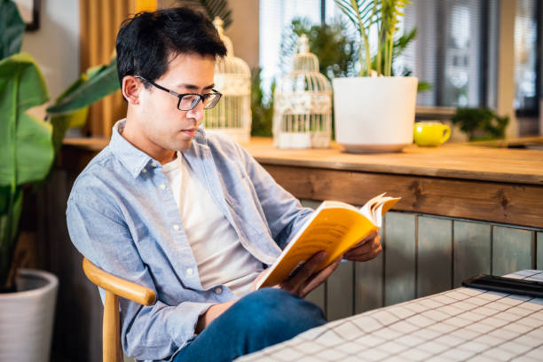 istock Asian man reading a book in a cafe 1159741382
