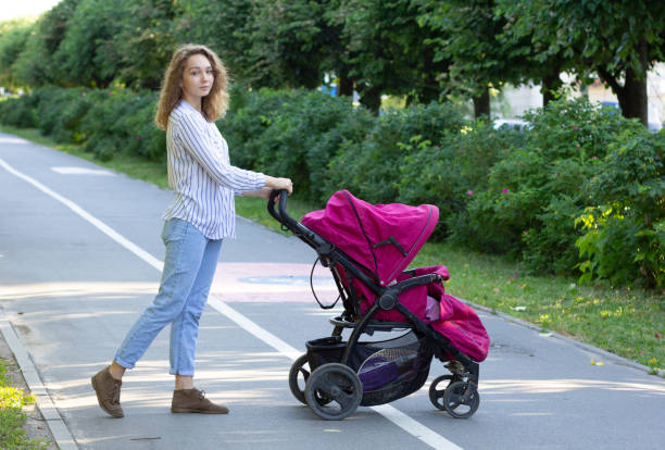 istock Young mother with newborn in stroller walking in park 1159741425