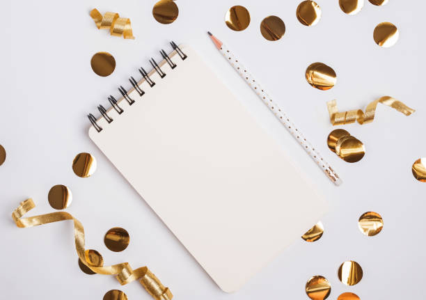 istock Empty paper notepad  lying on the table with golden color decor and tinsel. 1159742338
