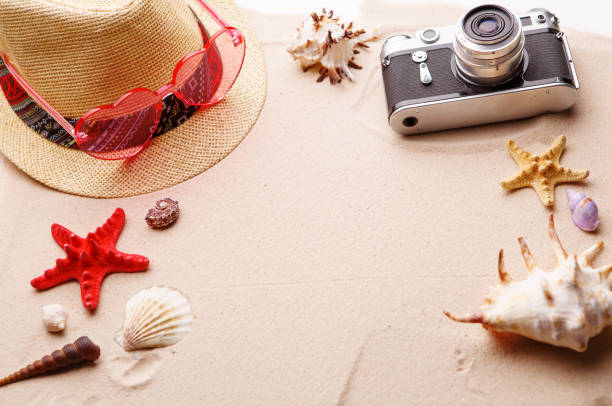 istock Beach accessories - sunglasses, hat and camera on sand witn shells and seastar. 1159744744