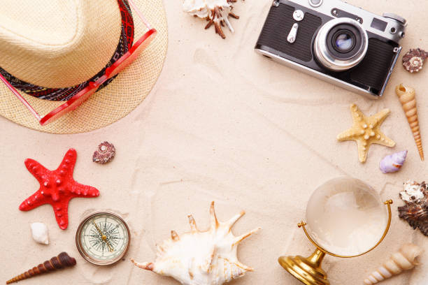 istock Beach accessories - sunglasses, hat and camera on sand witn shells and seastar. 1159744796