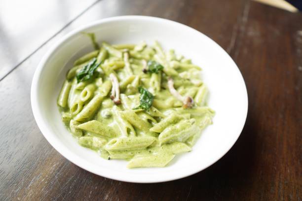 istock Creamy penne pesto pasta served on a table in a restaurant. 1159746179
