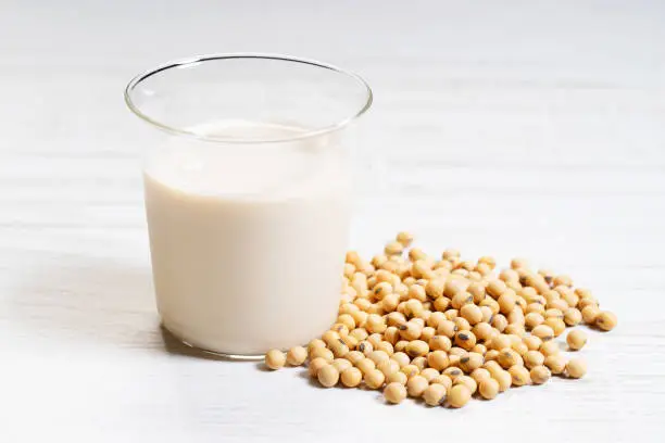 soymilk on white wooden table with soybeans