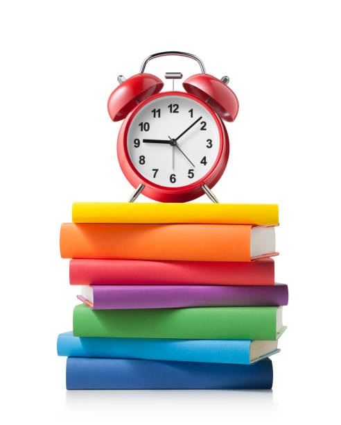 istock Alarm clock on stack of colored books on white background 1159751787