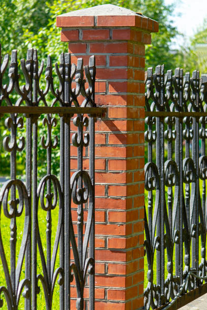 istock Black metal fence with brick pillars. 1159752466