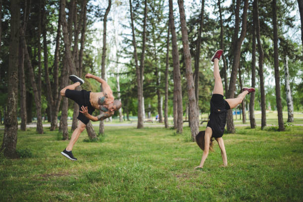 Young couple training in public park Young caucasian couple training parkour in public park. handspring stock pictures, royalty-free photos & images