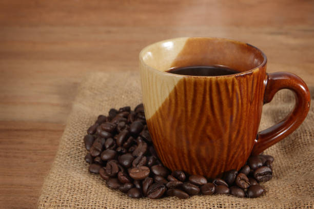 istock Coffee cup and coffee beans on old wooden 1159754509