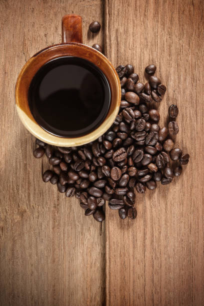 istock Coffee cup and coffee beans on old wooden 1159754515