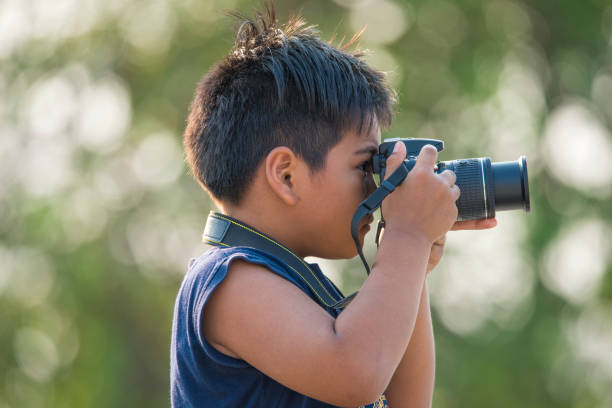istock The boy is holding a camera in his hand. 1159755939