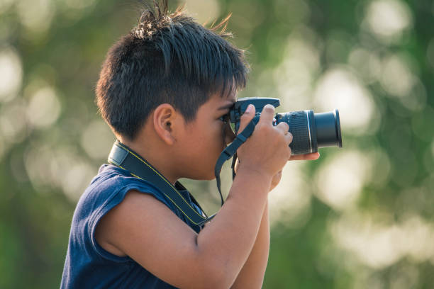 istock The boy is holding a camera in his hand. 1159756888