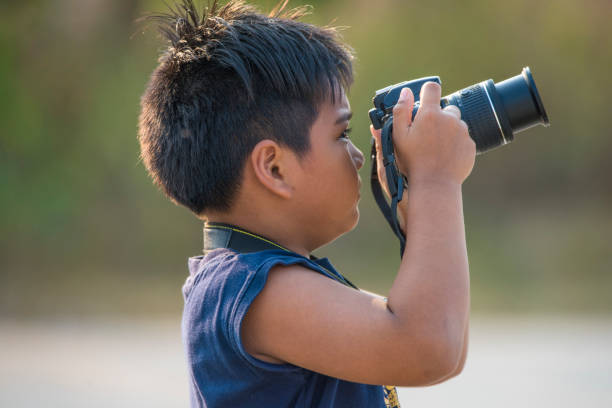 istock The boy is holding a camera in his hand. 1159757180
