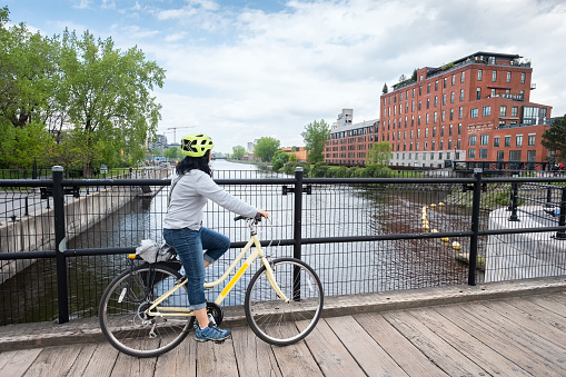 Tourist with rental bike crossing a bridge over the Lachine Canal, Montreal, Quebec, Canada