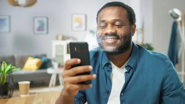 Photo of Young Man Identified by Biometric Facial Recognition Scanning Process from His Smartphone. Futuristic Concept: Projector Identifies Individual by Illuminating Face by Dots and Scanning with Laser