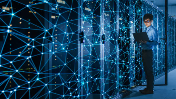 shot of a asian it engineer using laptop in a data center server room. concept of internet web visualization projection with blue lines on server rack. - network server rack computer mainframe imagens e fotografias de stock