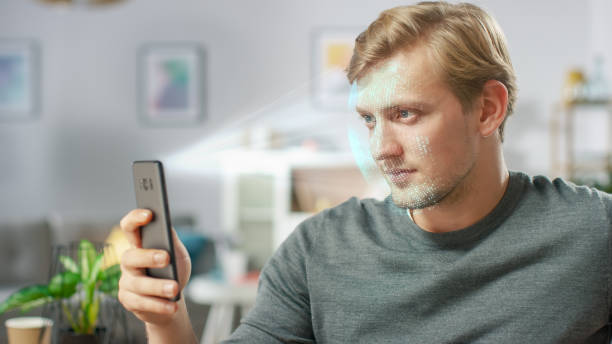 istock Young Man Identified by Biometric Facial Recognition Scanning Process from His Smartphone. Futuristic Concept: Projector Identifies Individual by Illuminating Face by Dots and Scanning with Laser 1159763221