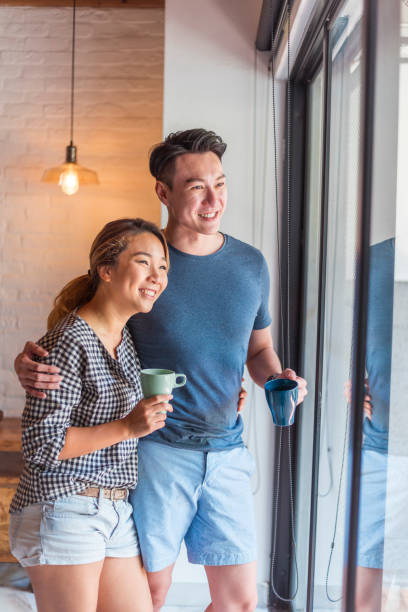 istock Young Asian couple looking out through window 1159764943
