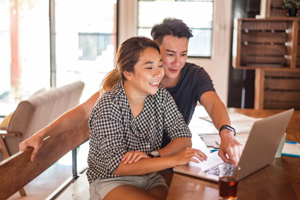 istock Young Asian couple sitting at the table and using laptop 1159764946