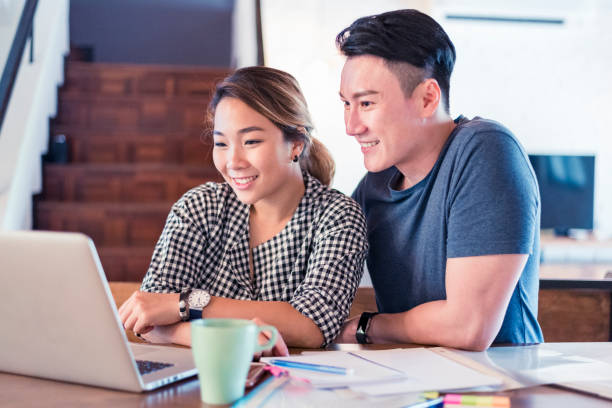 istock Young Asian couple sitting at the table and using laptop 1159764951