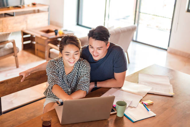 istock Young Asian couple sitting at the table and using laptop 1159764956