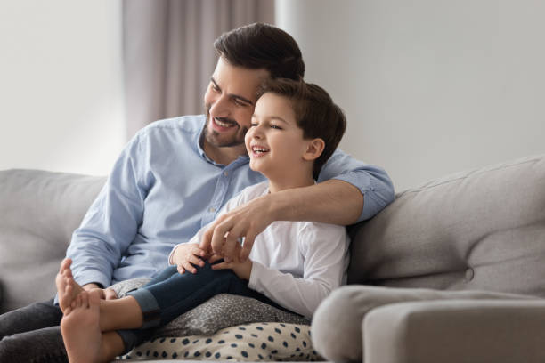 istock Smiling dad and son relax cuddling on sofa at home 1159765332