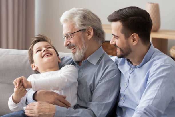 tre generazioni di uomini si divertono a rilassarsi insieme - grandfather adult affectionate little boys foto e immagini stock