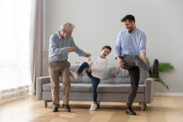Happy three generations of men dancing together Happy three generations of men have fun dancing feel overjoyed in living room, smiling millennial father, preschooler son and grandfather entertain relaxing at home, laugh moving to rhythm together dancing dad stock pictures, royalty-free photos & images