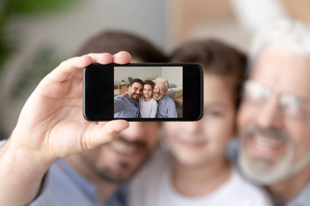 istock Smiling three generations of men take selfie on smartphone 1159765859