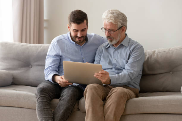 istock Grown son and senior dad using laptop at home together 1159765883