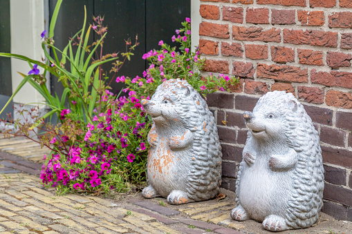Two white smiling hedgehogs and flowers as decoration in the street in front of a house