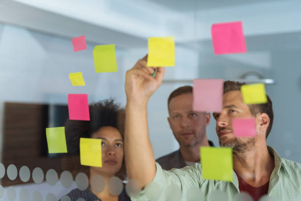 istock Coworkers discussing new ideas on a glass wall 1159767538