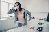 Close up photo beautiful she her lady hot beverage swallow sip croissant table late job quickly dressing jacket blazer exhausted formal-wear checkered plaid costume bright white kitchen indoors