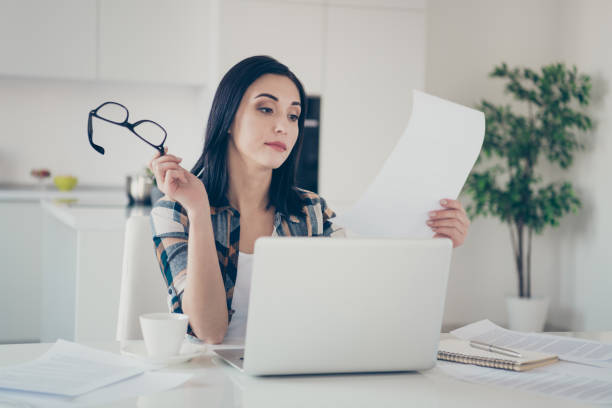 istock Portrait of beautiful charming youth hold hand have documentation data look eyewear eyeglasses laptop editor entrepreneur sit desk table light apartment wear checkered shirt plaid 1159774098