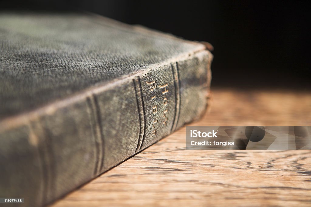 Leather covered bible lying on a table Leather covered old bible lying on a wooden table in a beam of sunlight (not an isolated image) VERY SHALLOW Depth of field – Focus on Text “Holy Bible” Anglican Stock Photo