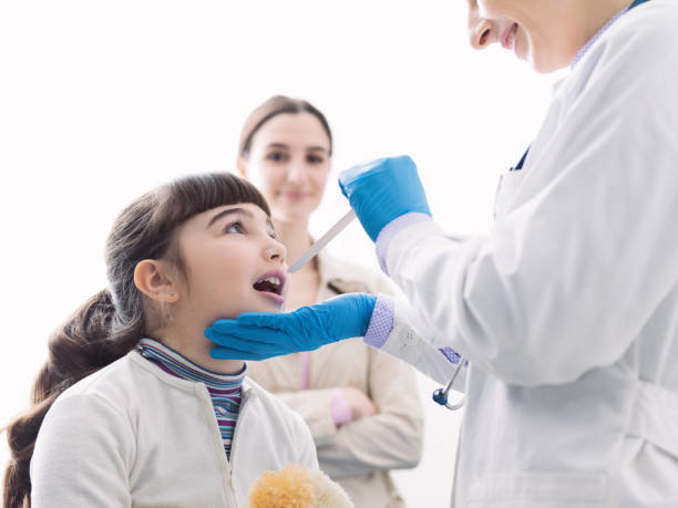 istock Doctor checking a girl's throat during a visit 1159774440