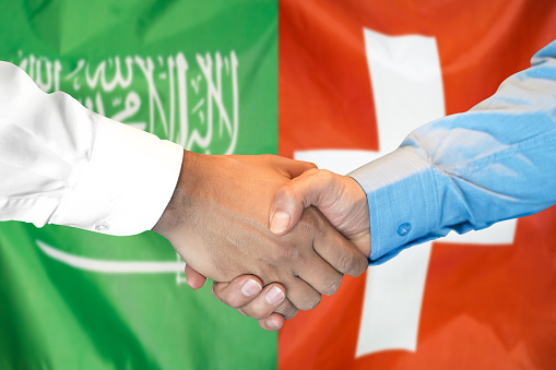 Business handshake on the background of two flags. Men handshake on the background of the Saudi Arabia and Switzerland flag. Support concept