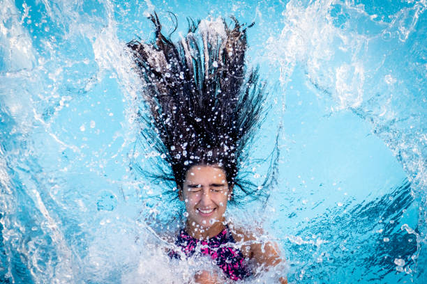 young man is swimming in a outdoor pool, out of focus and backlit