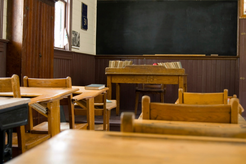 A student's view of the teacher's desk and blackboard in an old school building. The black board can be used for copy space.
