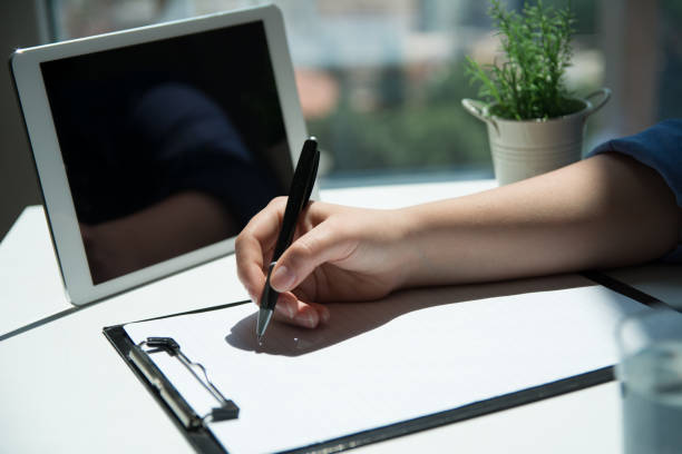 istock Business woman hand is writing on a notepad with a pen. Close up 1159785340