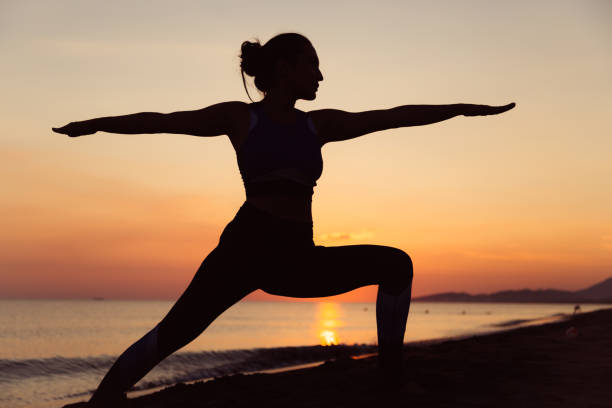 Woman doing yoga by the beach Woman meditating and doing yoga by the beach yoga stock pictures, royalty-free photos & images