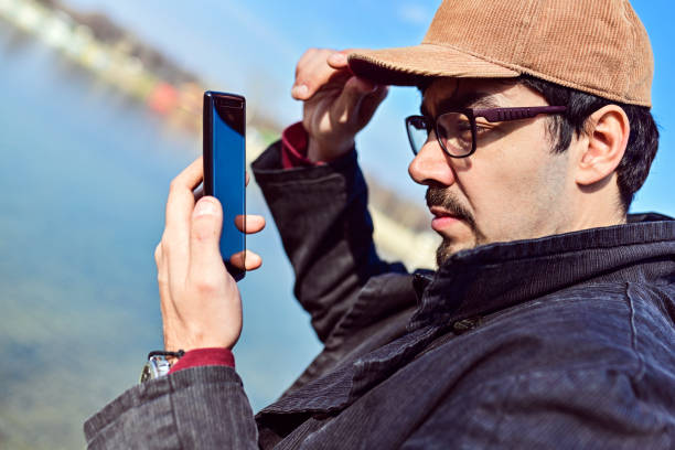istock Man at a lake with mobile 1159788730