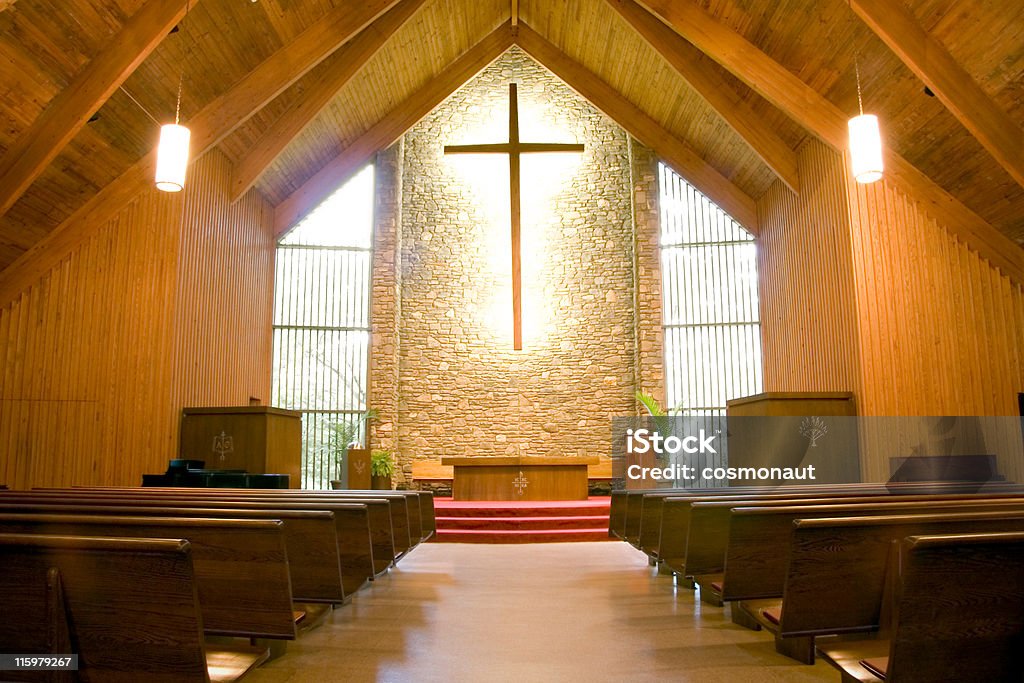 Orange highlights in a church interior with cross The view from the aisle of a Christian church. Built Structure Stock Photo