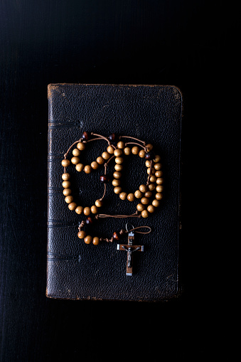 Cuentas del Rosario y libro de oración. Rosario y libro de liturgia de la Iglesia Católica sobre fondo oscuro. photo