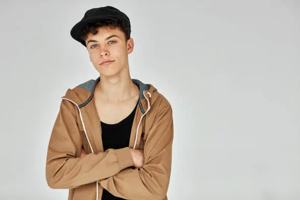 Handsome confident boy with crossed arms wear cap and looking and camera, isolated on white background