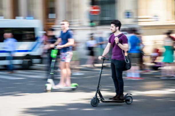 um homem novo monta um scooter elétrico na alta velocidade nas ruas de paris, france. - paris france audio - fotografias e filmes do acervo
